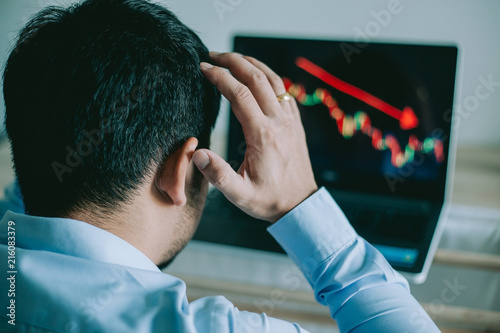 Stress Business man look at to the laptop show financial market chart graphic going down.  Stock market concept.