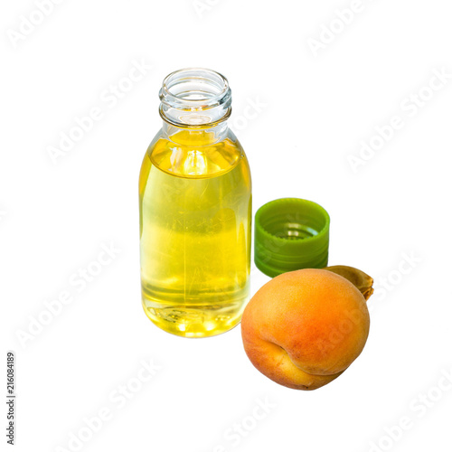   A small bottle of butter and a fresh ripe apricot on a white background.