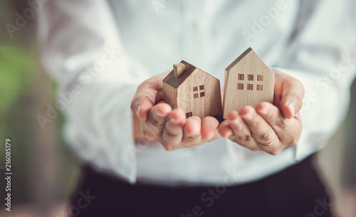 Hand of woman holding a toy house. Home safety , Home care , Home for sale concept.