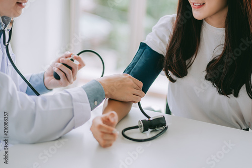 Doctor using sphygmomanometer with stethoscope checking blood pressure to a patient in the hospital.