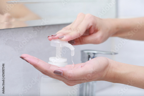 Female hands using wash hand sanitizer gel pump dispenser.