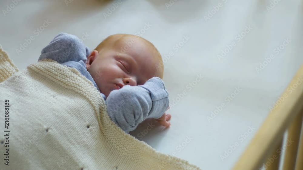 Mother cover her baby with a blanket in a white bed, warm concept and