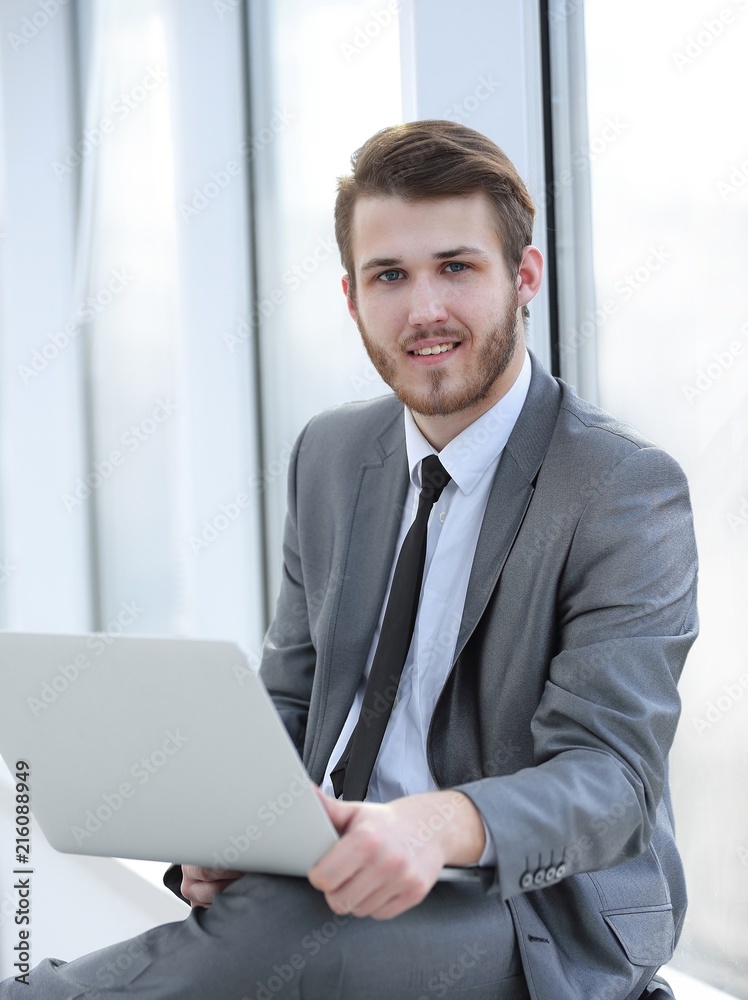 young professional with laptop on background of office window young professional with laptop on background of office window