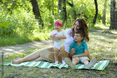 Happy family. Mother with the little daughter and the son have a rest in the park.