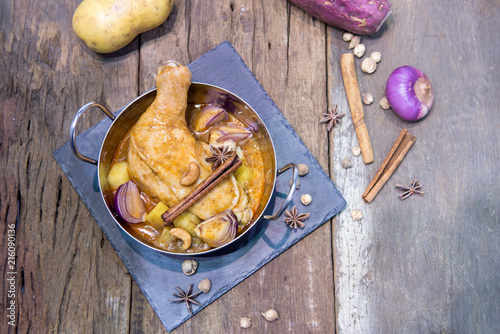 Still life food of Chicken mussaman curry in bowl on wooden background with Thai herb. photo