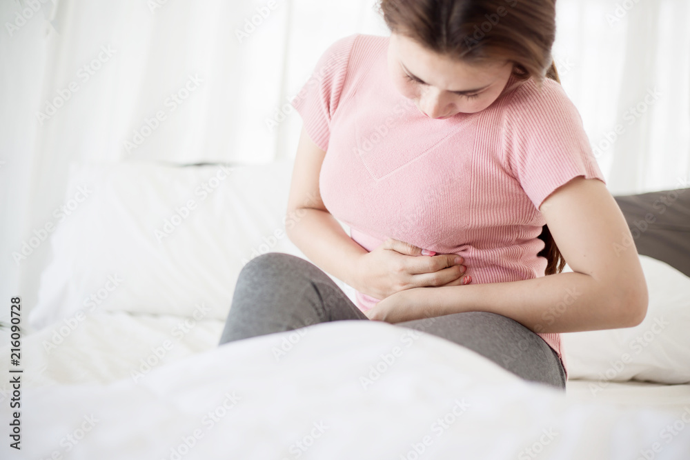 Young asian woman suffering from abdominal pain on the bed. Young asian woman suffering from abdominal pain on the bed.