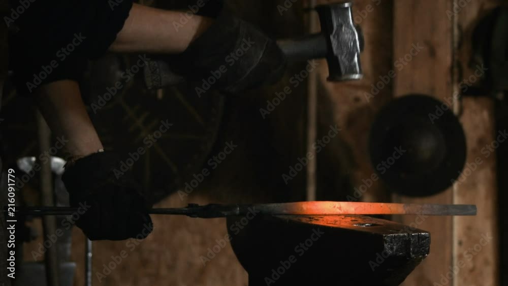 Blacksmith manually forging the molten metal on the anvil in slowmotion Blacksmith manually forging the molten metal on the anvil in slowmotion