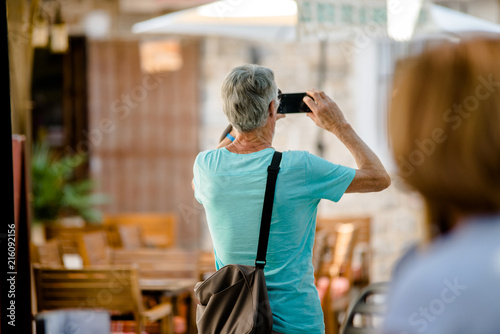 An elderly tourist photographs the sights of the old town.