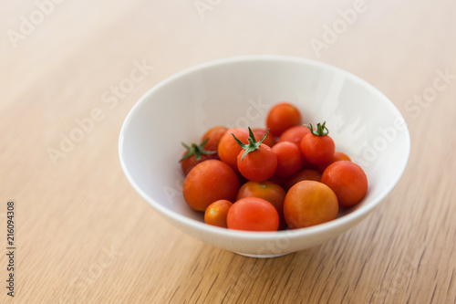 many red cherry tomatoes on the bowl wood table