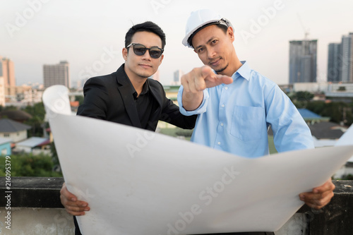 Businessman working with Architect  Engineer on the rooftop Construction Site with blueprint.