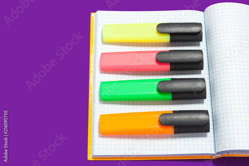 new bright colored markers lying on a copybook . concept of office accessories