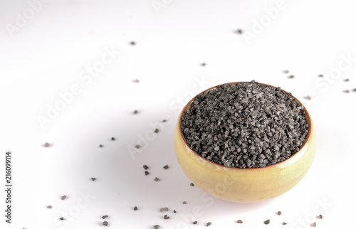 Himalayan black rock salt used in South Asia, the Himalayas, Pakistan in a stone bowl on a white background photo