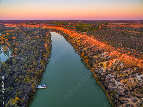 Aerial landscape of sandstone cliffs over Murray RIver and moored houseboat at sunset