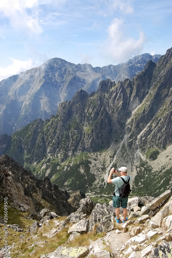 In the summer, the tourist takes pictures of the mountain peaks of the High Tatras.
