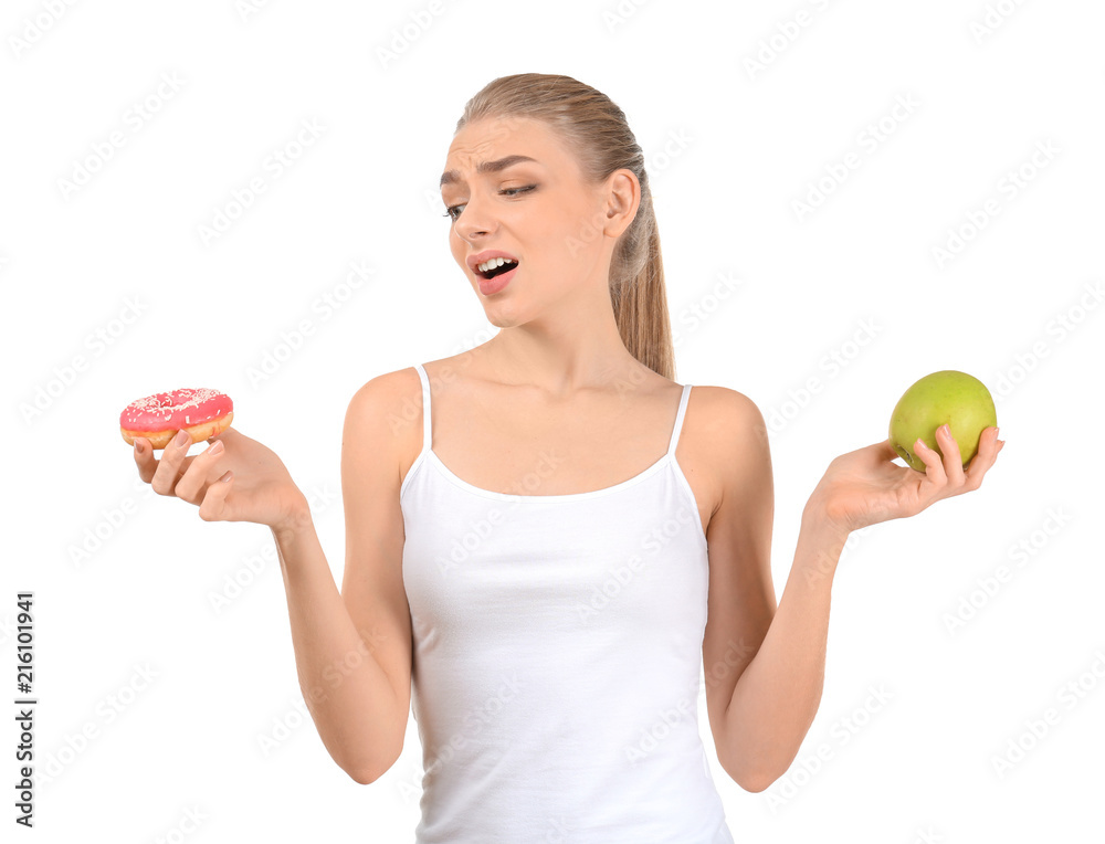 Young woman choosing between donut and apple on white background. Diet food concept Young woman choosing between donut and apple on white background. Diet food concept