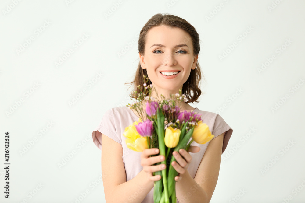 Beautiful woman with bouquet of flowers on light background Beautiful woman with bouquet of flowers on light background