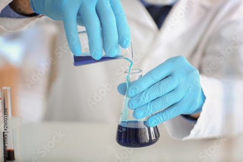 Scientist pouring sample into test flask in laboratory