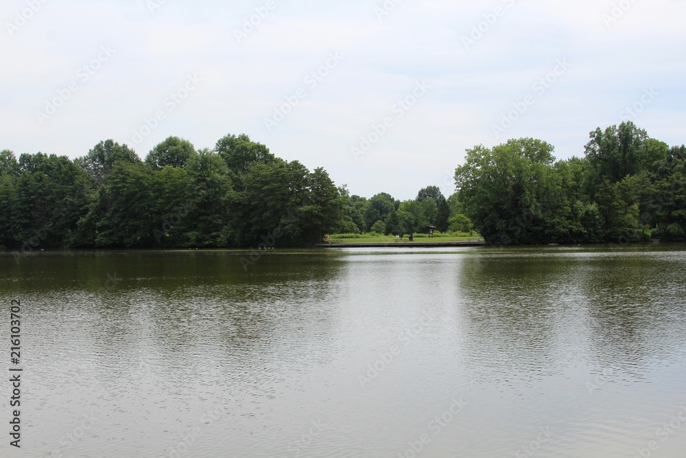 The calm peaceful lake in the park on a cloudy day.