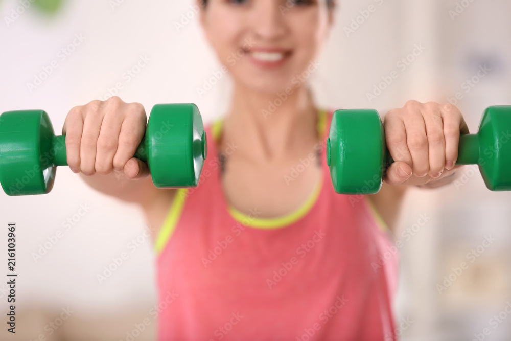 Beautiful young woman doing exercises with dumbbells at home in morning Beautiful young woman doing exercises with dumbbells at home in morning