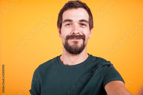 Close up selfie portrait of happy smiling man isolated on yellow background