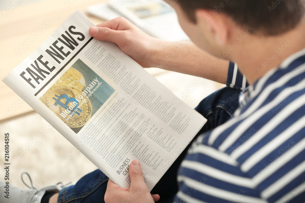 Naklejka premium Handsome man reading newspaper at home