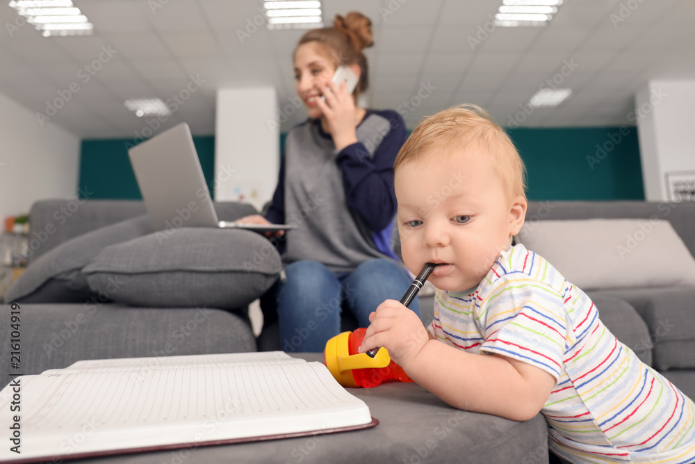 Cute little baby playing with notebook while mother working at home Cute little baby playing with notebook while mother working at home