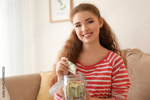 Young woman putting dollar ...