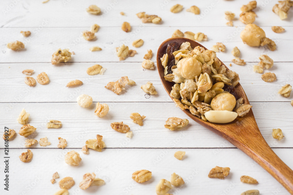 Fototapeta premium Dry Breakfast of oat flakes, granules and nuts. Muesli on a light table in a wooden spoon.