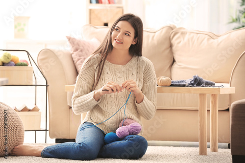 Young woman knitting indoors