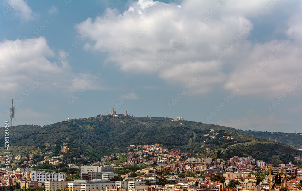View to the Tibidabo mountain with Sagrat Cor church and Amusement Park atop. The Torre de Collserola telecommunications tower is to the left. All three are prominently visible from most of the city.