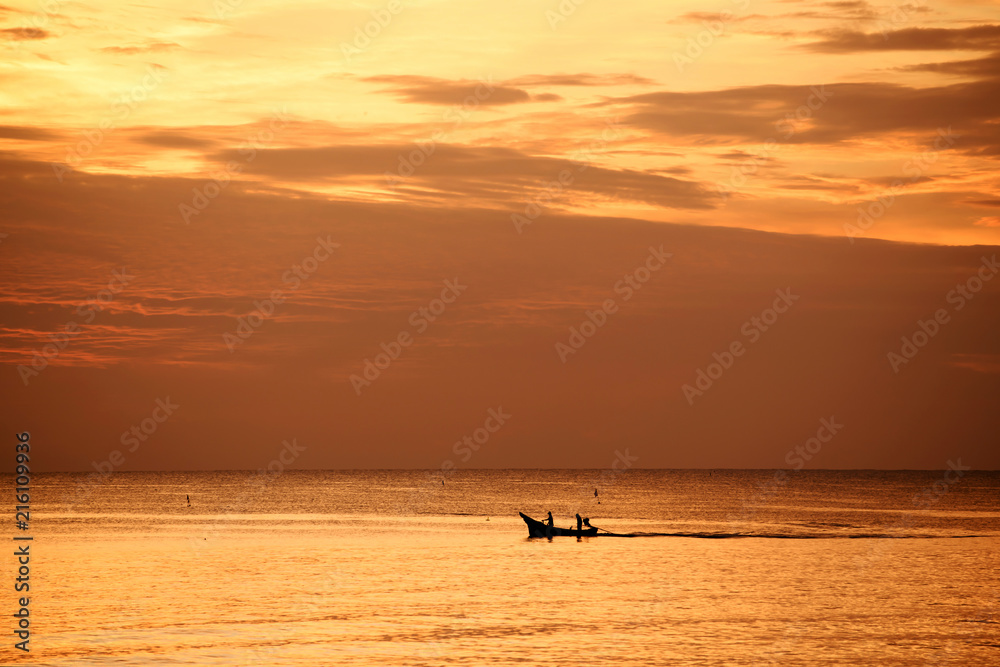 Fototapeta premium Fishermen out fishing at sunrise in the sea, amidst the clouds and the sky is beautiful