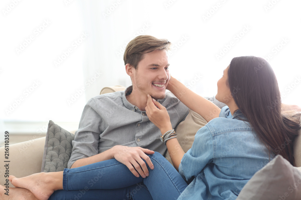 Happy young couple resting on sofa at home
