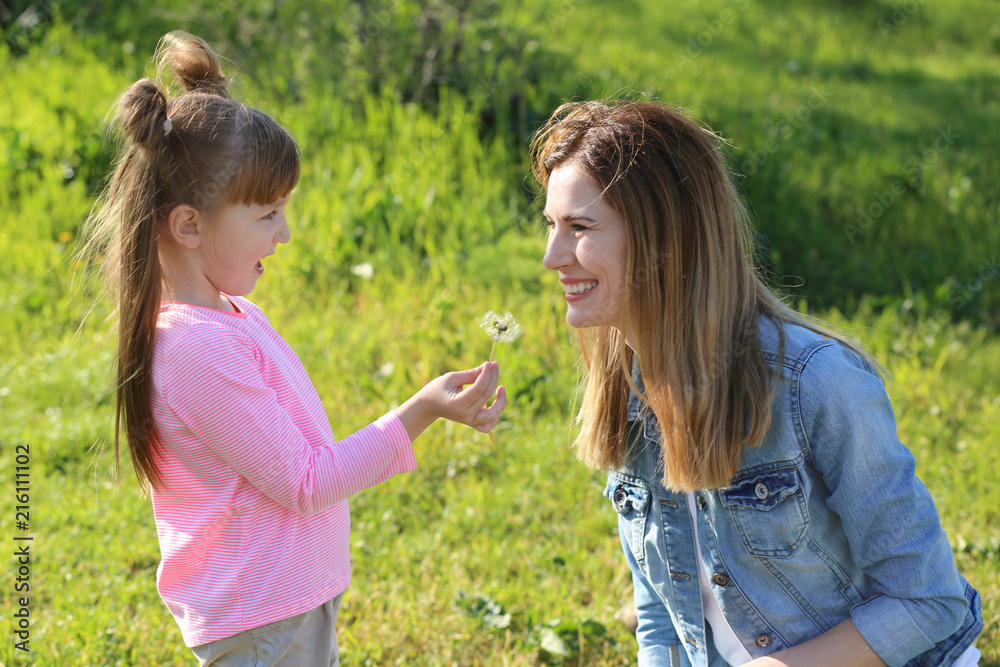 Mother and little daughter with dandelion in park Mother and little daughter with dandelion in park
