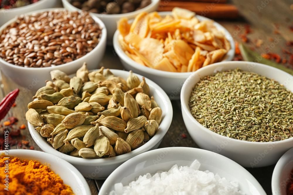Bowls with various spices on wooden table, closeup