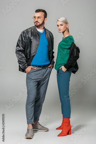 fashionable couple of models in stylish autumn outfits on grey background © LIGHTFIELD STUDIOS