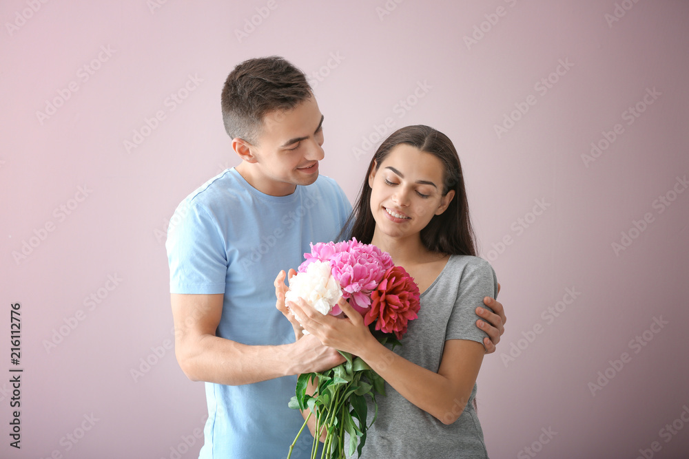 Young man giving beautiful flowers to his beloved girlfriend on color ...