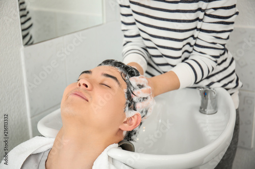 Barber washing client's hair in beauty salon