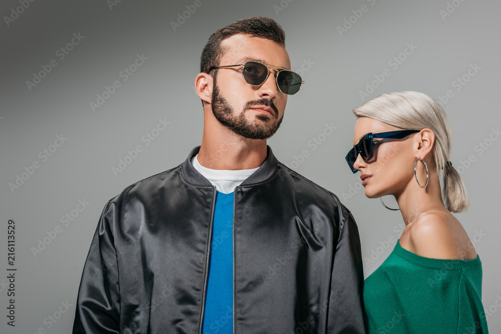 fashionable couple posing in sunglasses, isolated on grey fashionable couple posing in sunglasses, isolated on grey