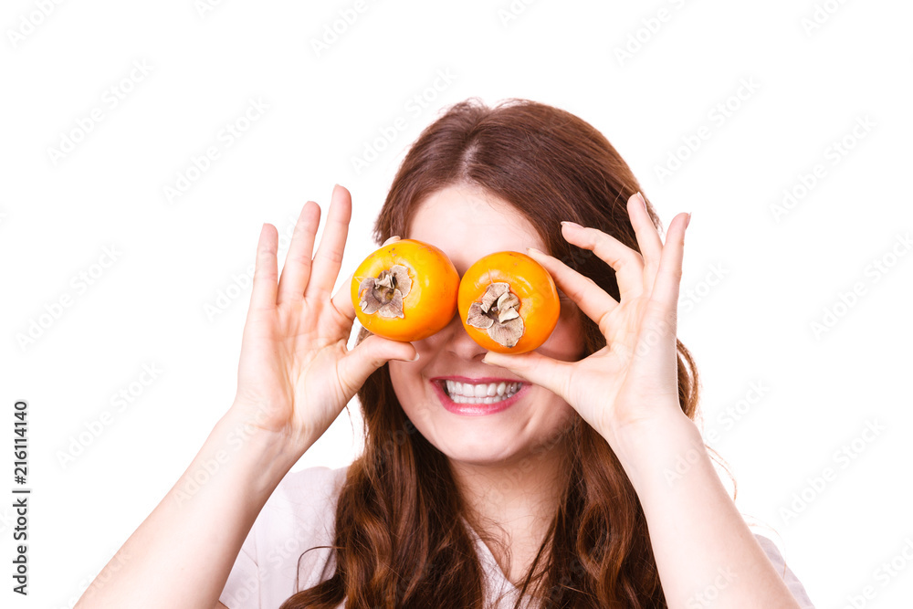 Woman holds persimmon kaki fruits on eyes, isolated Woman holds persimmon kaki fruits on eyes, isolated