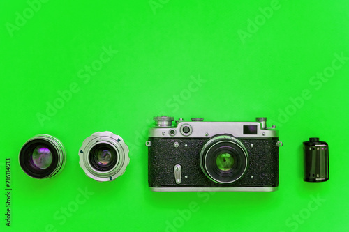 Vintage film photo camera lens film roll and accessories on green colourful trendy modern fashion pin-up background. Technology development photographer hobby classic memory trip concept. Top View
