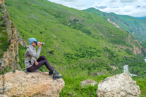 A girl in the mountains is resting. Young woman on a background of a mountain landscape.