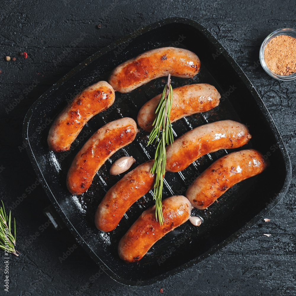 Top view on fried sausages in a black frying pan on a black stone table