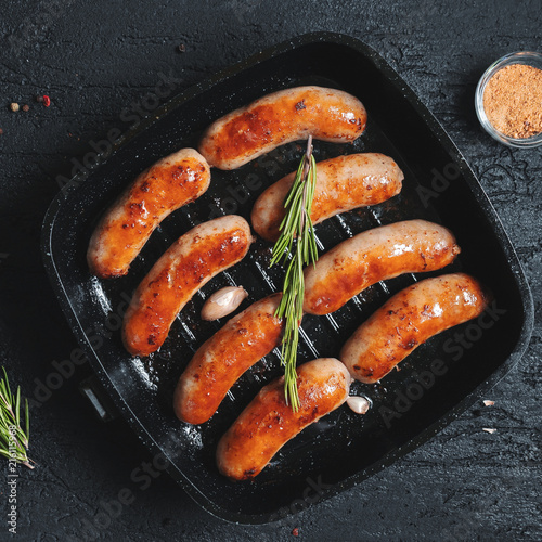 Obraz na płótnie Top view on fried sausages in a black frying pan on a black stone table w salonie