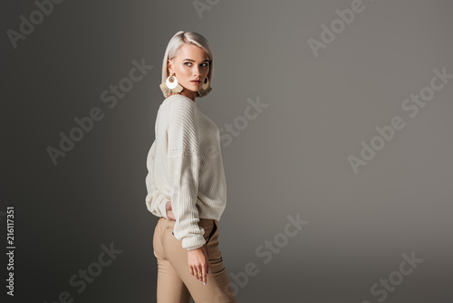 attractive girl posing in white sweater, isolated on grey