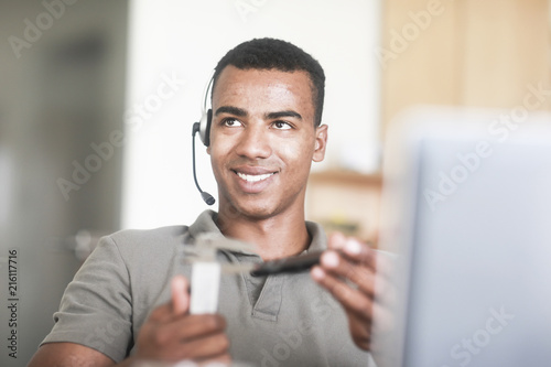 Junger Mann mit Messinstrument an einem Schreibtisch photo