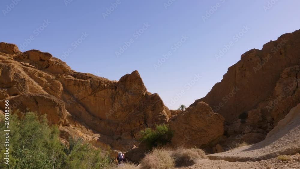 Tourist people walking through sandy canyon in Oasis Chebika in Sahara desert Tourist people walking through sandy canyon in Oasis Chebika in Sahara desert