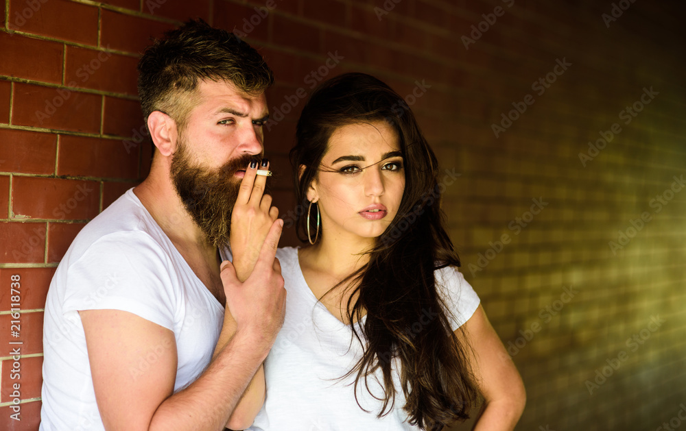 Couple in love hugs while smoking cigarette brick wall background ...