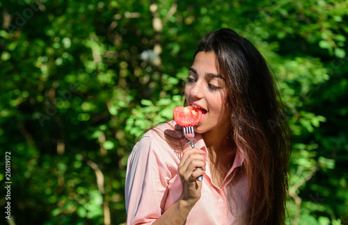 Girl holds fork with juicy ripe tomato. Lady attractive brunette eats tomato. Seductive appetite. Girl seductive eats red vegetable. Woman full of desire hungry eating tomato. Her appetite is sexy