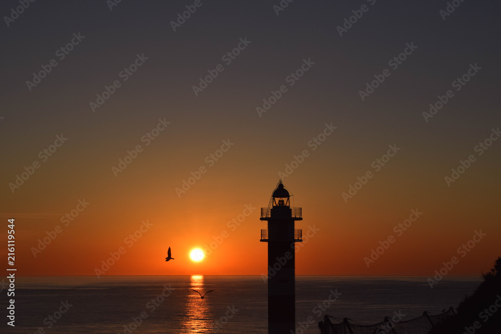 Silhouete of a lighthouse at sunrise.