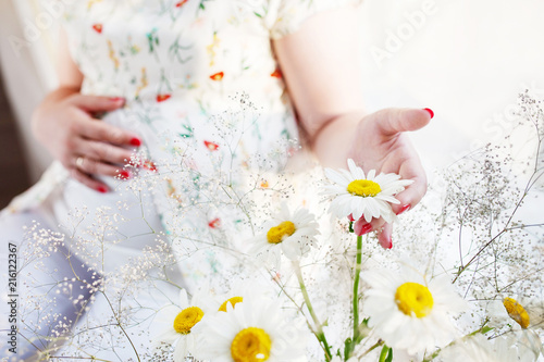 Closeup of pregnant woman holding flower and touching her belly © fadzeyeva